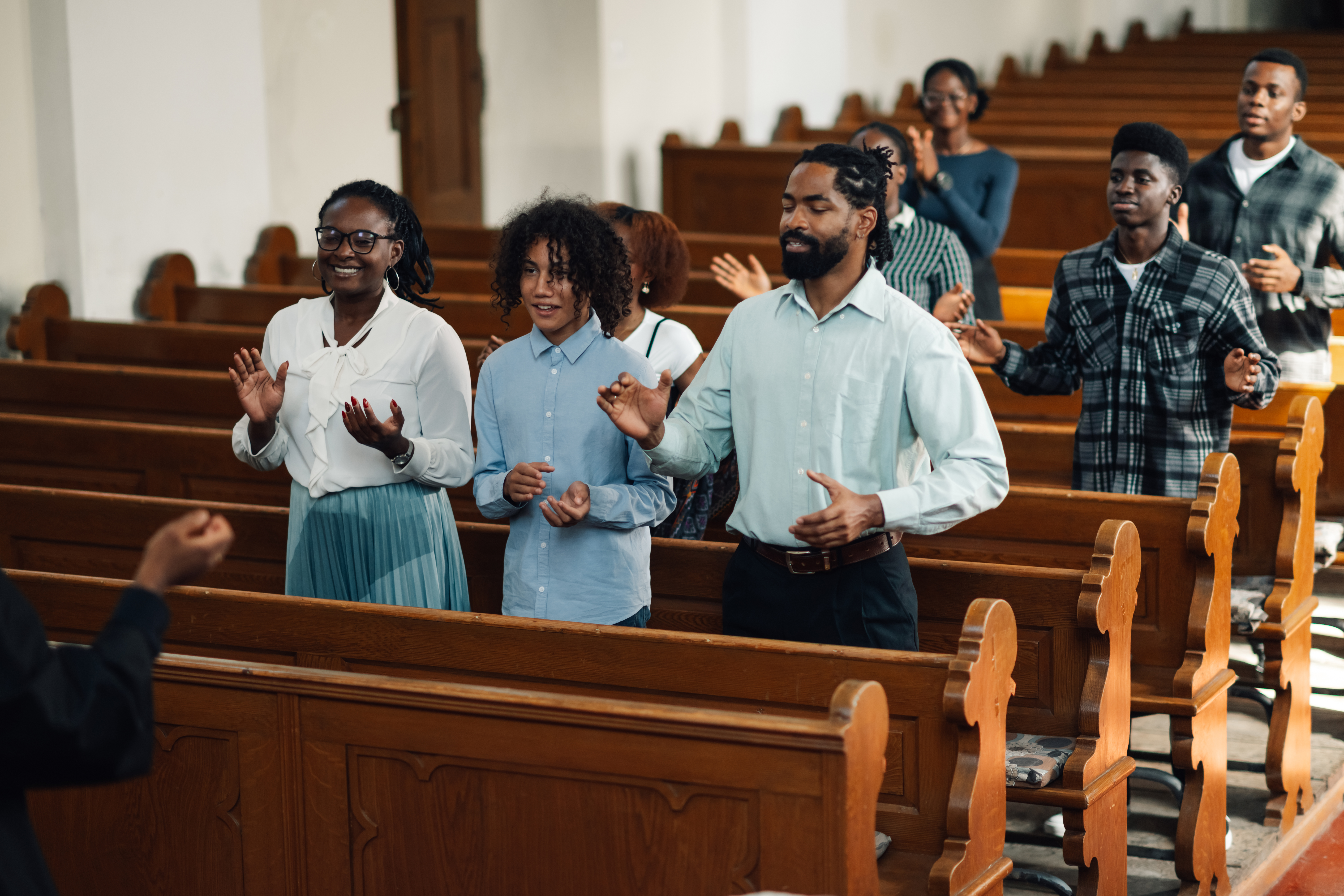 Congregation standing and praying with arms raised in worship.