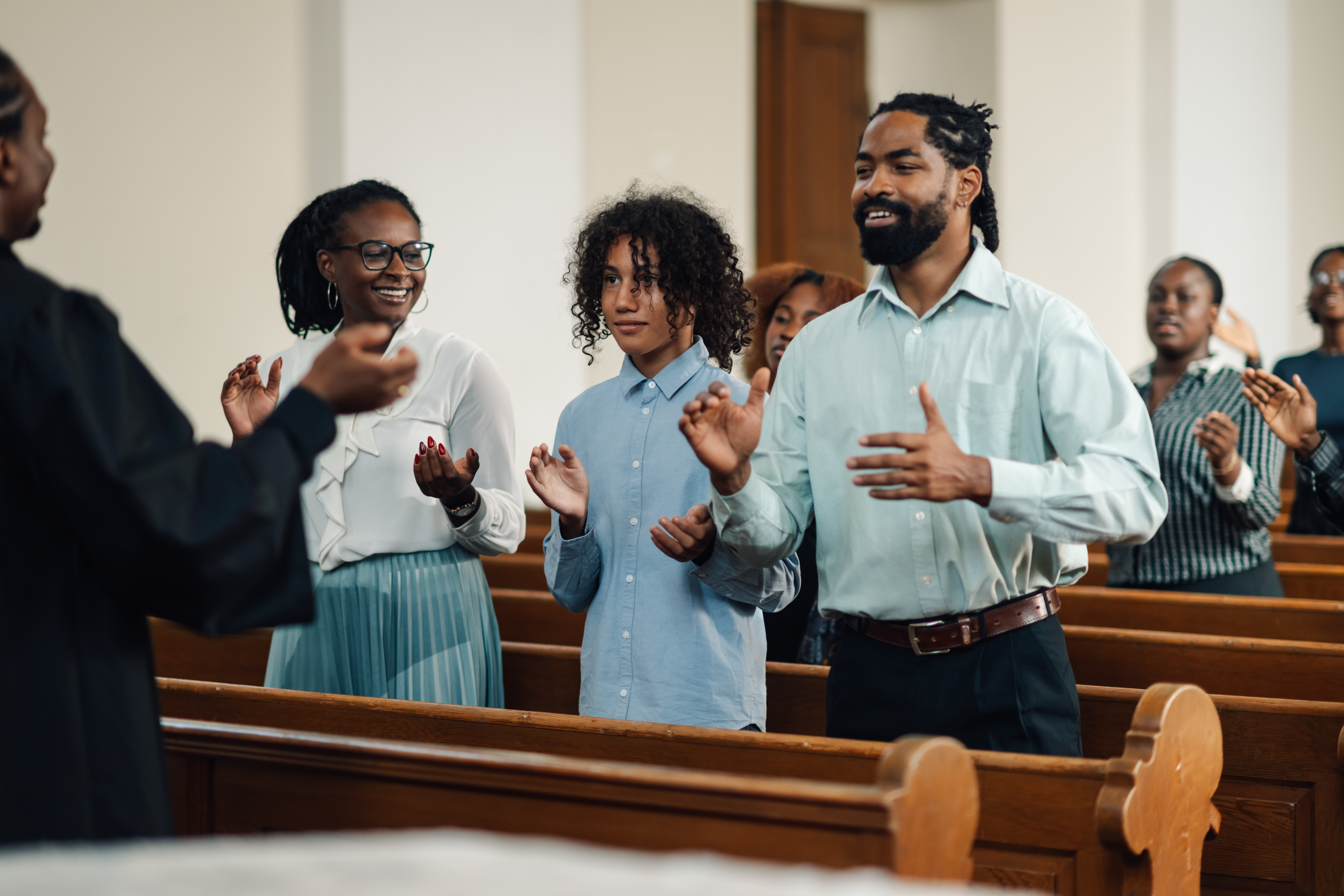 Group of people clapping and singing at a church service.