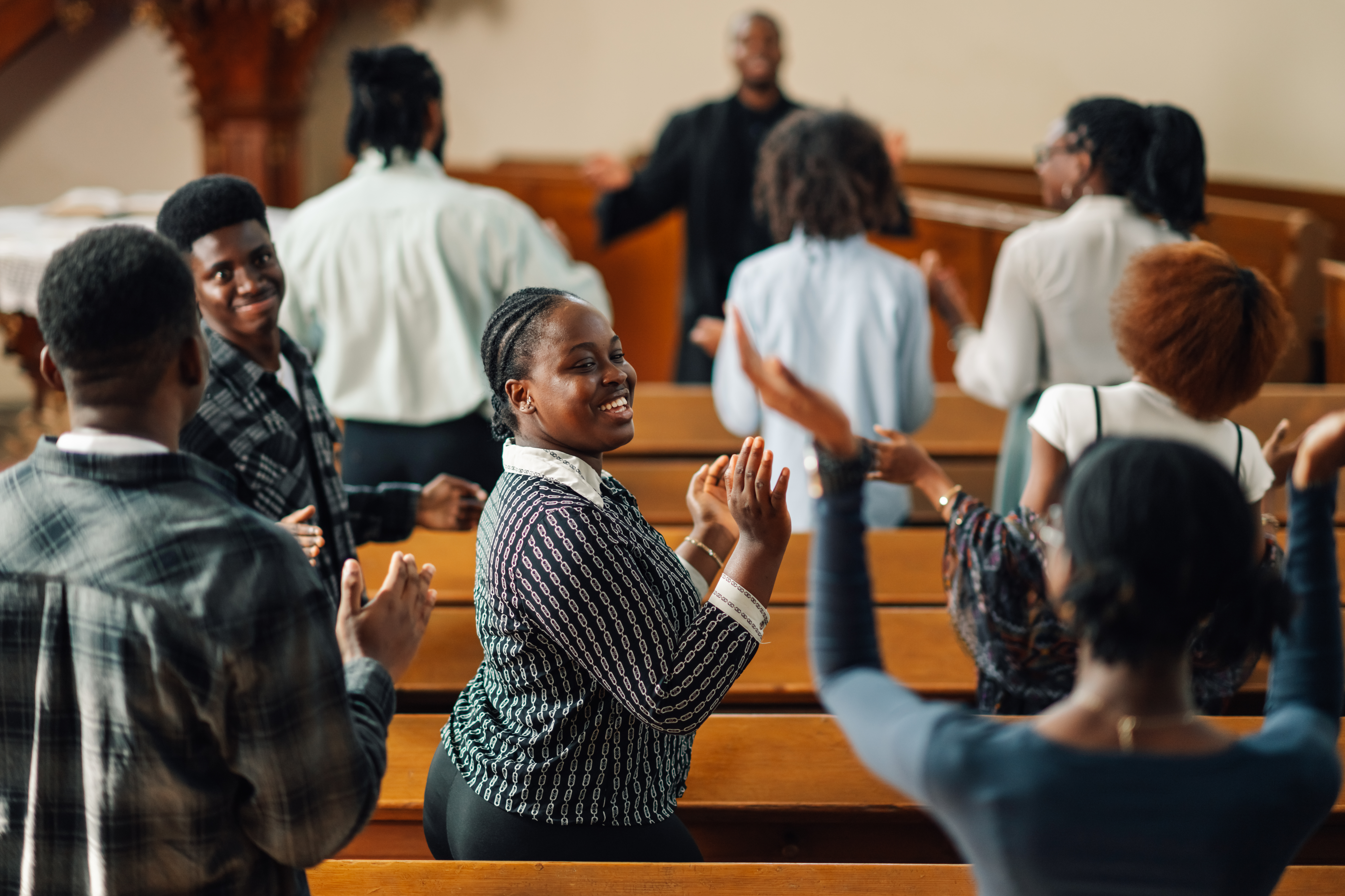 Group of people clapping hands and singing gospel music in church.