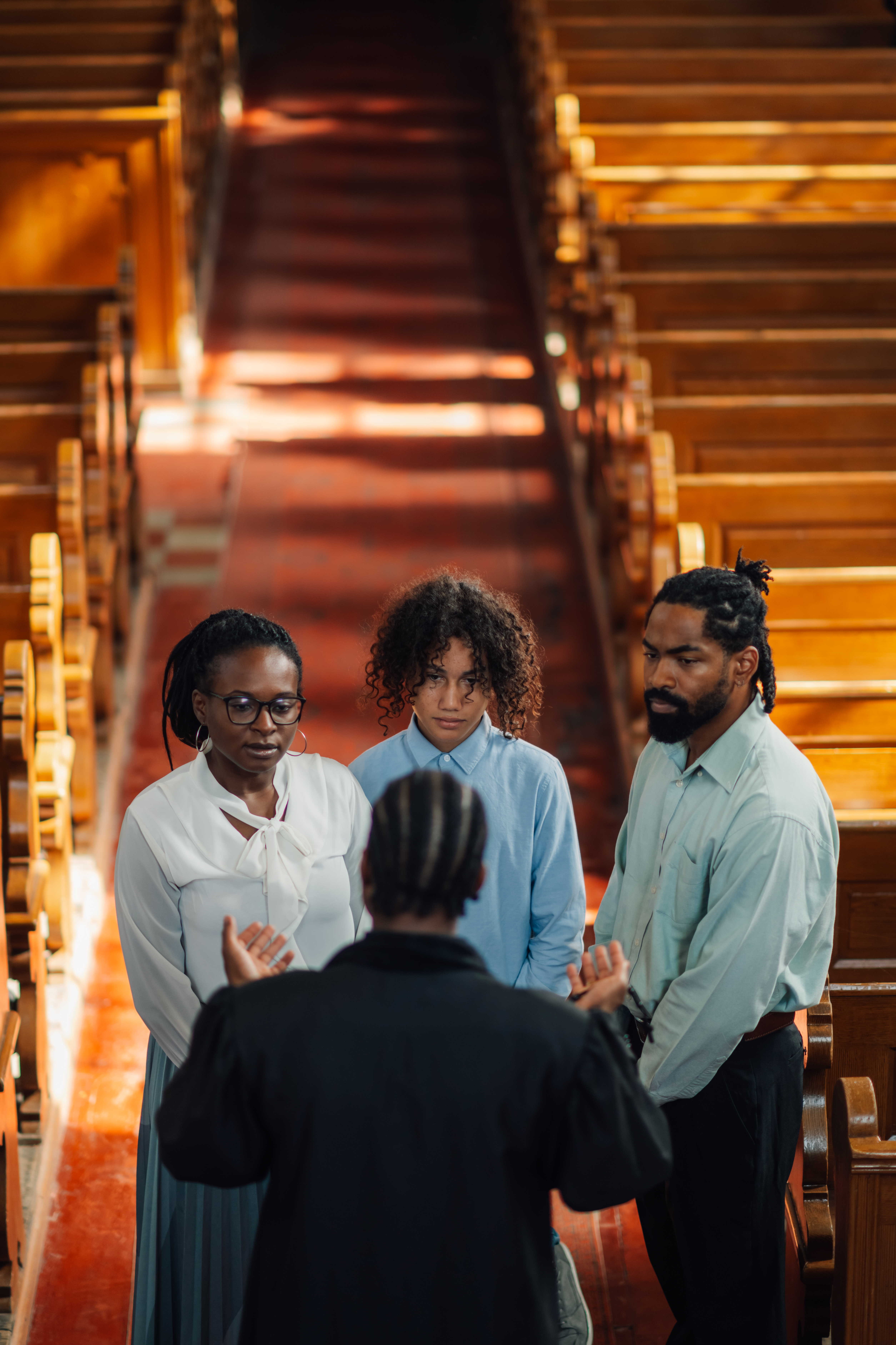 Priest speaking with family in church after Sunday service fellowship.